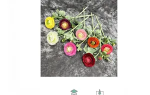 Flat lay of artificial ranunculus flowers in multiple colors on a dark fabric background