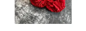 Close-up of two bright red artificial carnations with realistic velvet-textured petals