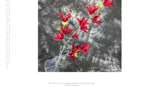 Detail view of artificial red lily flower with yellow stamens in a glass vase