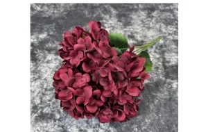 Close-up of burgundy artificial hydrangea with realistic silk petals and green leaf veins