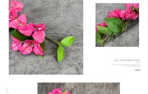Close-up of vibrant pink silk bougainvillea flowers with green leaves on grey surface