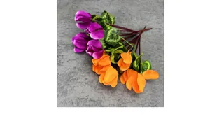 Detail of lifelike purple and orange cyclamen silk flowers with realistic green leaves