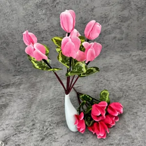 Artificial pink cyclamen bouquet with green marbled leaves in a white ceramic vase