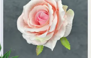 Macro detail of matte fabric rose head in pink gradient with realistic green sepals