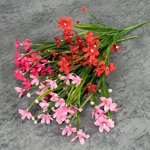 Lebhafter künstlicher Orchideenstrauß mit roten und rosa Blüten und grünen Blättern