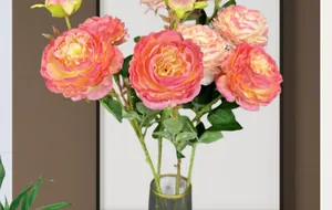 Detail van roze kunstmatige pioenrozen met groene stelen in een glazen vaas met gouden rand