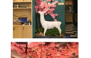 Detail of pink artificial cherry blossom decor with white deer sculpture for interior design