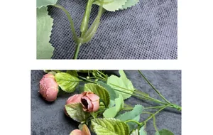 Detail of faux rose buds featuring pink-orange petals and realistic green leaf texture