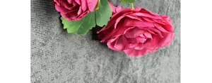 Detailopname van roze kunstmatige rozen met zijden bloembladen en groene bladeren