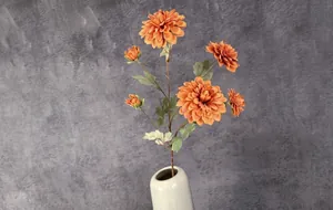 Détail macro de dahlias artificiels orange dans un vase en céramique sur fond gris rétro