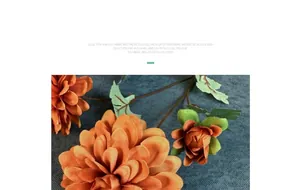 Gros plan d'une fleur de dahlia en soie orange avec des feuilles sur tissu gris