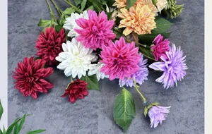 Flat lay view of artificial dahlia silk flowers with layered petals and green leaves