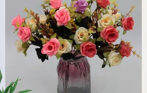 Détail de roses en soie colorées dans un vase en verre strié violet pour déco