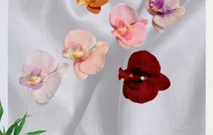 Detailed close-up of artificial orchid flower heads in various colors on white fabric