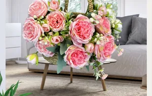 Gros plan d'un bouquet de pivoines artificielles roses dans un panier sur table en bois