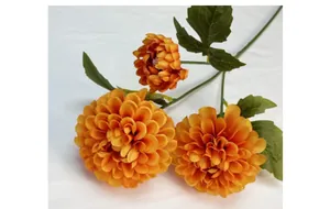 Macro-opname van kunstmatige oranje dahlia met stoffen bloembladen en groene bladeren