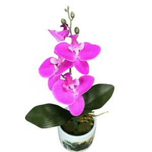 Donkerroze kunstmatige Phalaenopsis orchidee in een witte keramische pot met decoratie