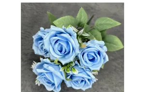 Detailed view of five blue artificial silk roses with green leaves on grey fabric