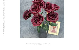Roses artificielles en soie rouge foncé dans un vase en verre gris avec feuilles vertes
