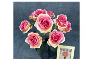 Détail de roses artificielles dégradées roses dans un vase en verre translucide sombre