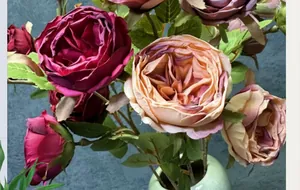Gros plan de roses Austin réalistes multicolores dans un vase en céramique sarcelle