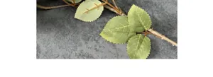 Détail de feuilles vertes artificielles avec bords dentelés et tiges marron réalistes