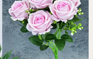 Detalle de rosas artificiales de terciopelo rosa con hojas verdes y flores de relleno