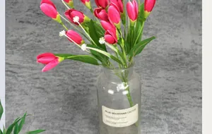 Macro shot of artificial magenta tulips in a glass vase against a grey background