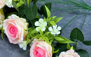Close-up of artificial gradient pink roses made of silk fabric with green leaves