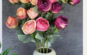 Detail of 5-head silk Milan roses in a white ceramic vase against a grey wall background