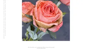Macro shot of realistic coral pink artificial ranunculus with layered petals and leaves