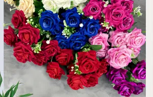 Detailed top view of multi-colored velvet artificial roses with green leaves on grey cloth