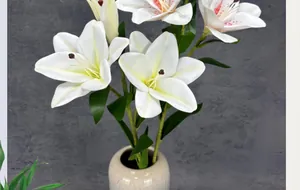 Detailed view of lifelike white lilies with 3 heads in a minimalist ceramic vase