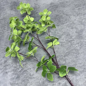 Close-up of artificial green plant branch with realistic leaf texture and dark brown stem
