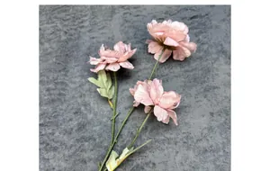 Detail of three artificial dusty pink gardenia flowers with green leaves on grey cloth