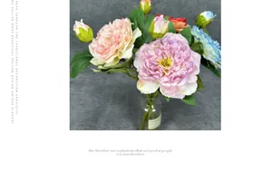 Detail showing artificial peonies in pink and blue with green leaves in a glass vase