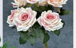Close-up of artificial rose bouquet with cream to pink gradient petals and green leaves