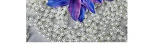 Detailed close-up of multi-layer white pearl necklace with purple floral accent decoration