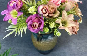 Detail of artificial rose and lily bouquet in a vintage glazed ceramic vase