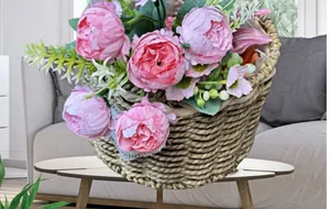 Composizione di peonie di seta rosa in cesto di vimini per decorazione del soggiorno