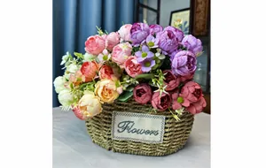 Detail of silk peony and rose bouquet in a rustic woven basket with Flowers patch