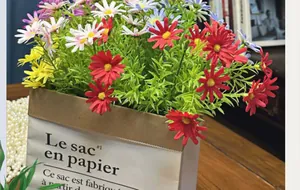 Close-up of colorful artificial daisies in a minimalist paper bag for home decor