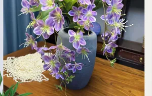 Detail of 3D printed purple silk jasmine flowers in a textured blue ceramic vase