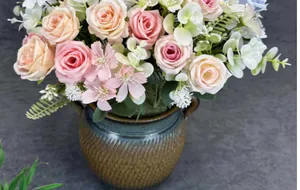Gros plan de roses artificielles dans un vase en céramique vintage avec poignées