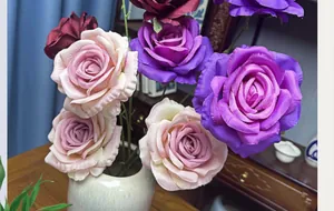 Détail de roses en soie violettes et roses dans un vase en céramique blanche décoratif