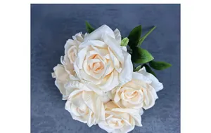 Close-up of artificial cream white silk roses with realistic petals and green leaves
