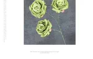 Gros plan de trois roses artificielles vertes en soie sur une surface grise mate
