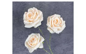 Détail macro de trois roses artificielles en soie crème avec pétales délicats et feuilles