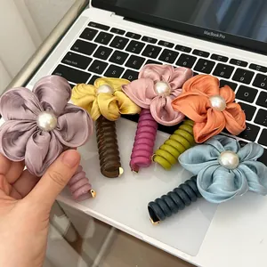 Detailed macro view of colorful floral hair ties featuring lustrous pearls and fabric petals