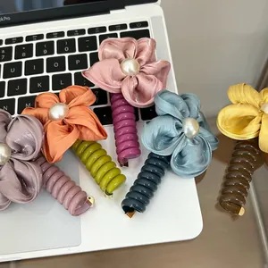 Macro shot of colorful spiral hair ties with fabric flowers and pearls on a desk